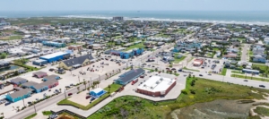 Aerial view of a colorful coastal town with buildings, roads, and the ocean in the background
